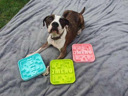 medium sized dog laid next to 3 medium sized puzzle bowls in various colours